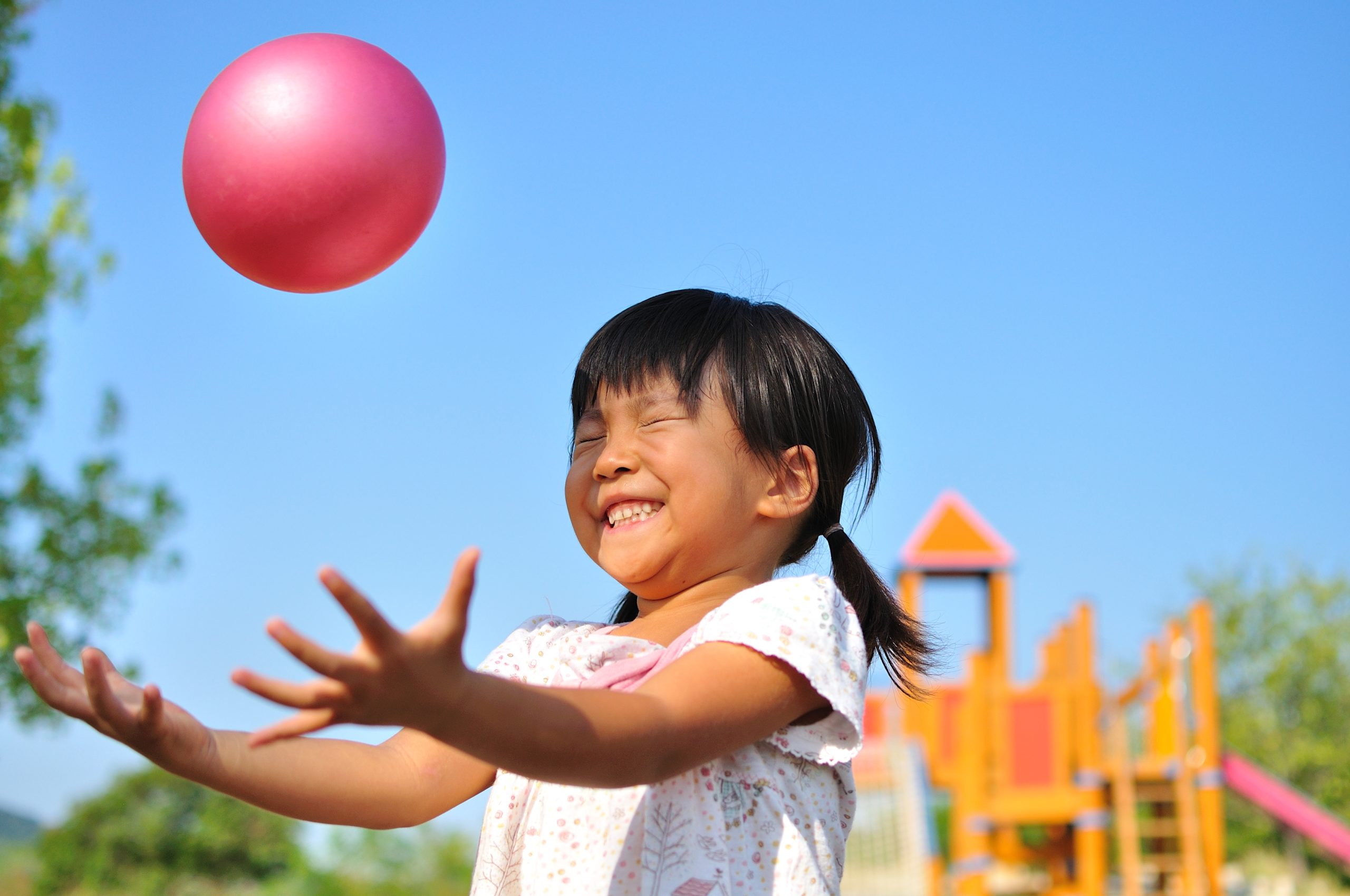 young girl smiling and playing with ball