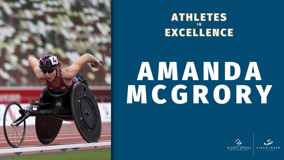 Woman in racing wheelchair propels herself forward next to the text Athletes in Excellence over Amanda McGrory