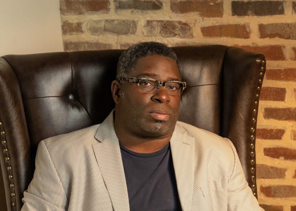 Man sitting in chair looks at camera solemnly